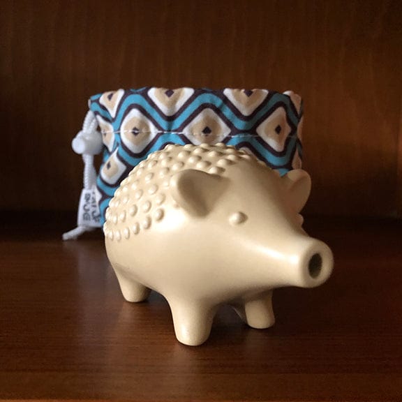 Front view of Helen the Hedgehog Pipe, a detailed ceramic piece with a colorful patterned cloth behind it.