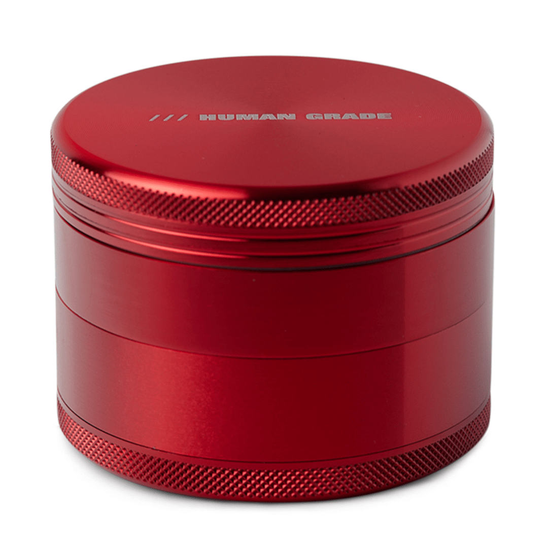 Front view of the Human Grade Grinder 1B (2.5”), a metallic red grinder with a textured, cylindrical design.