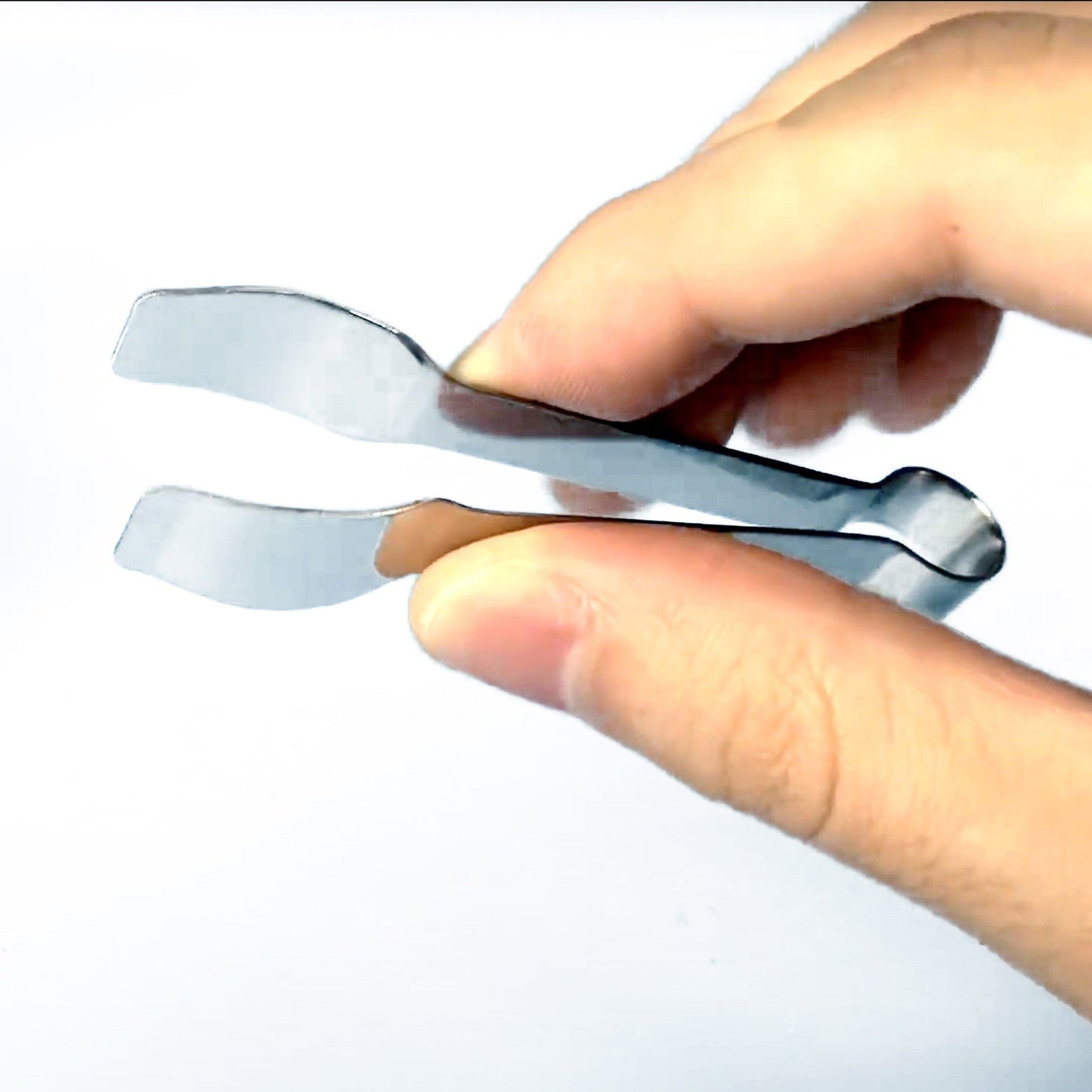 A close-up view shows the silver Vape Tweezers held between a person's fingers, showcasing their metallic finish and precision grip.