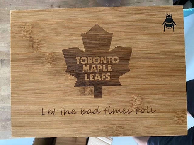 Front view of the XL Bamboo Bzz Box, a wooden stash box sitting on a dark surface in soft lighting.