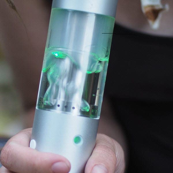A close-up, angled view of the Cloudious9 Hydrology9 Vaporizer with visible vapor inside its clear glass body.