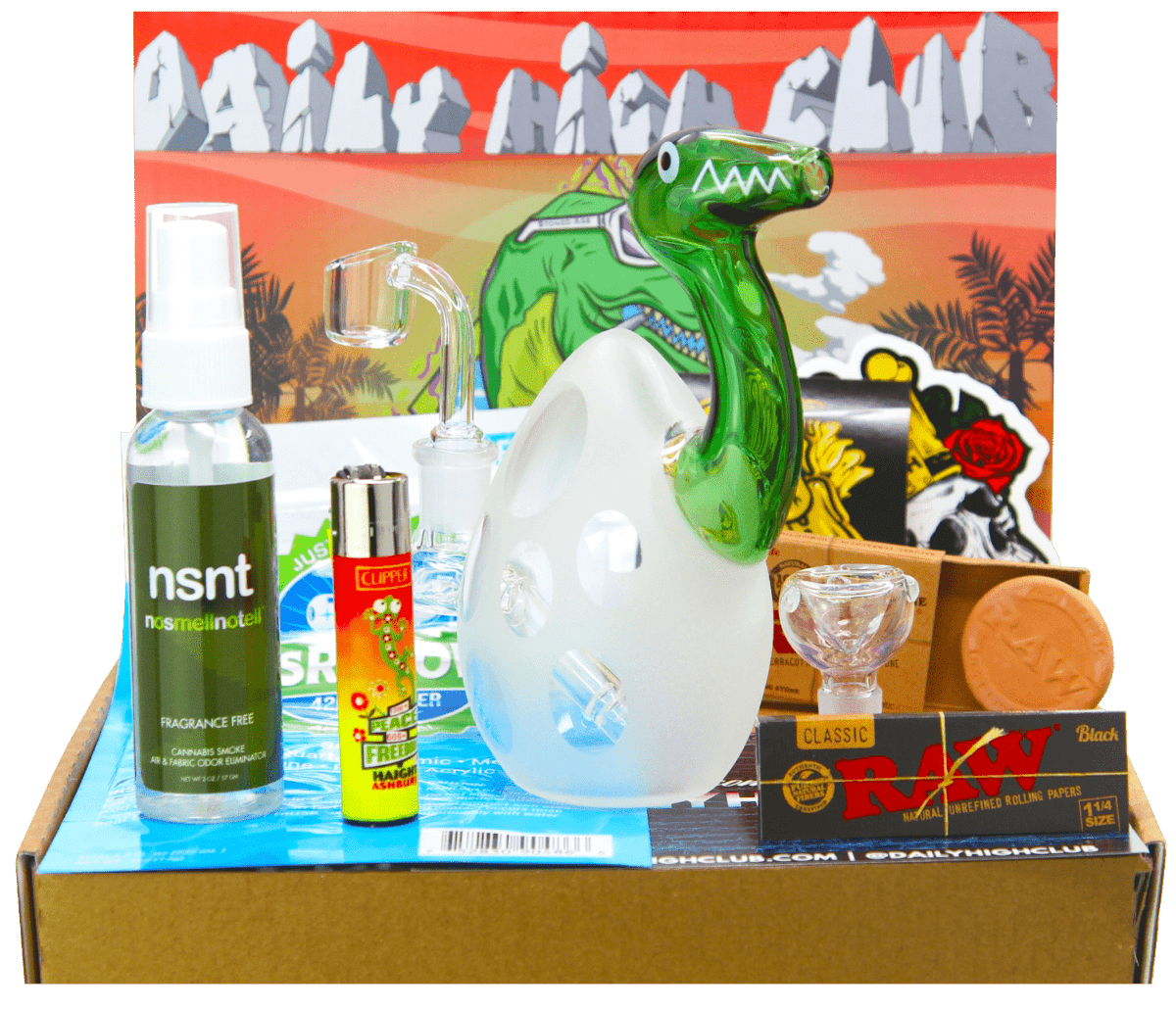 A top-down view of the “Jurassic Sesh” Smoking Box contents—a lighter, ashtray, and packaging—arranged on a brown surface.