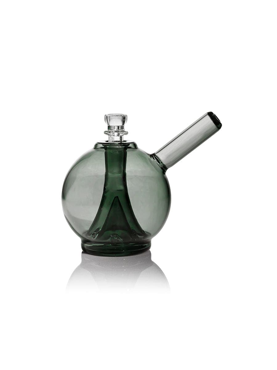 A three-quarter view of the GRAV® Globe Bubbler - Smoke, showing its rounded glass form reflected on a glossy surface.