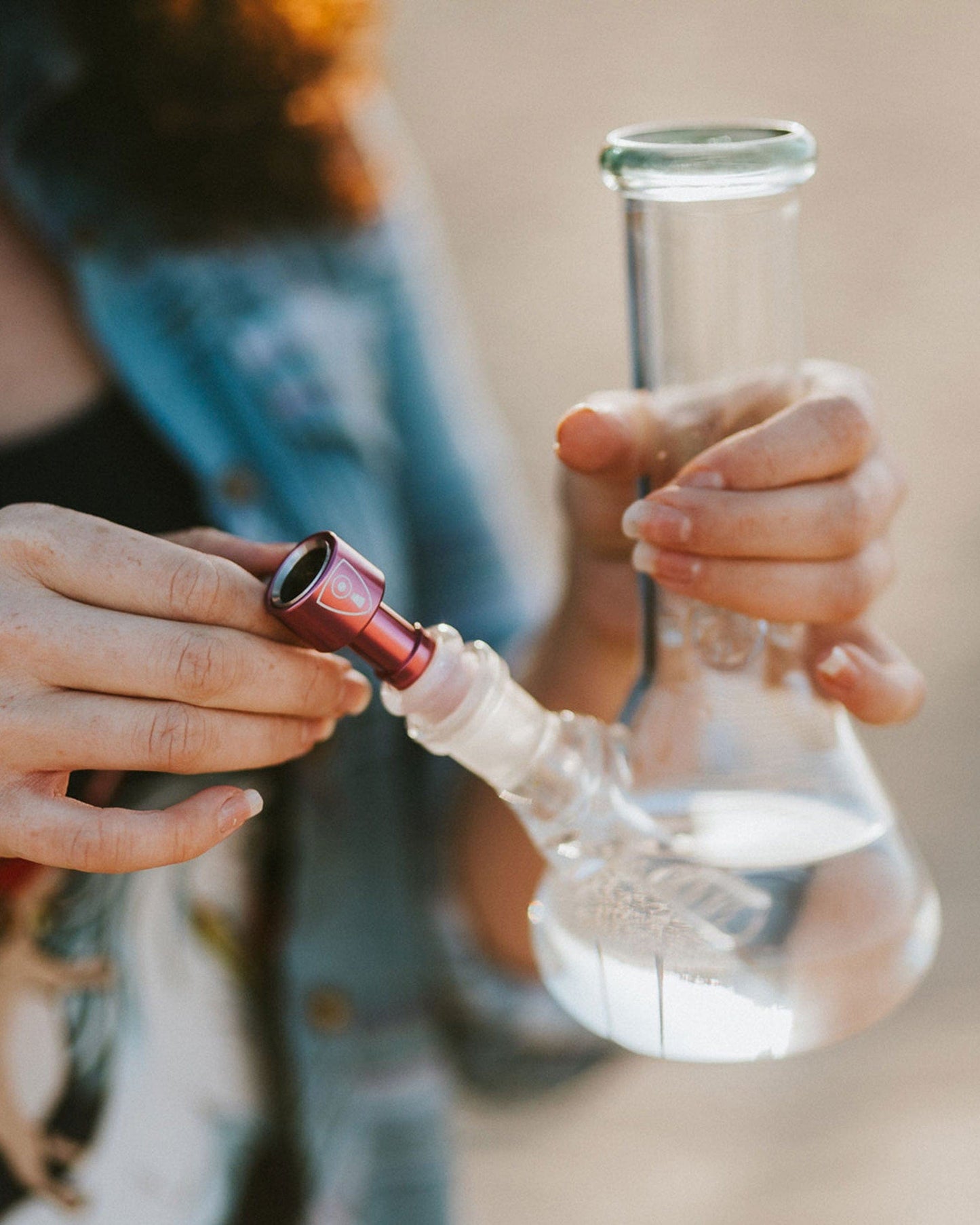 A close-up, angled view showcases the Indestructible Bong Bowl held by a person wearing a blue shirt.