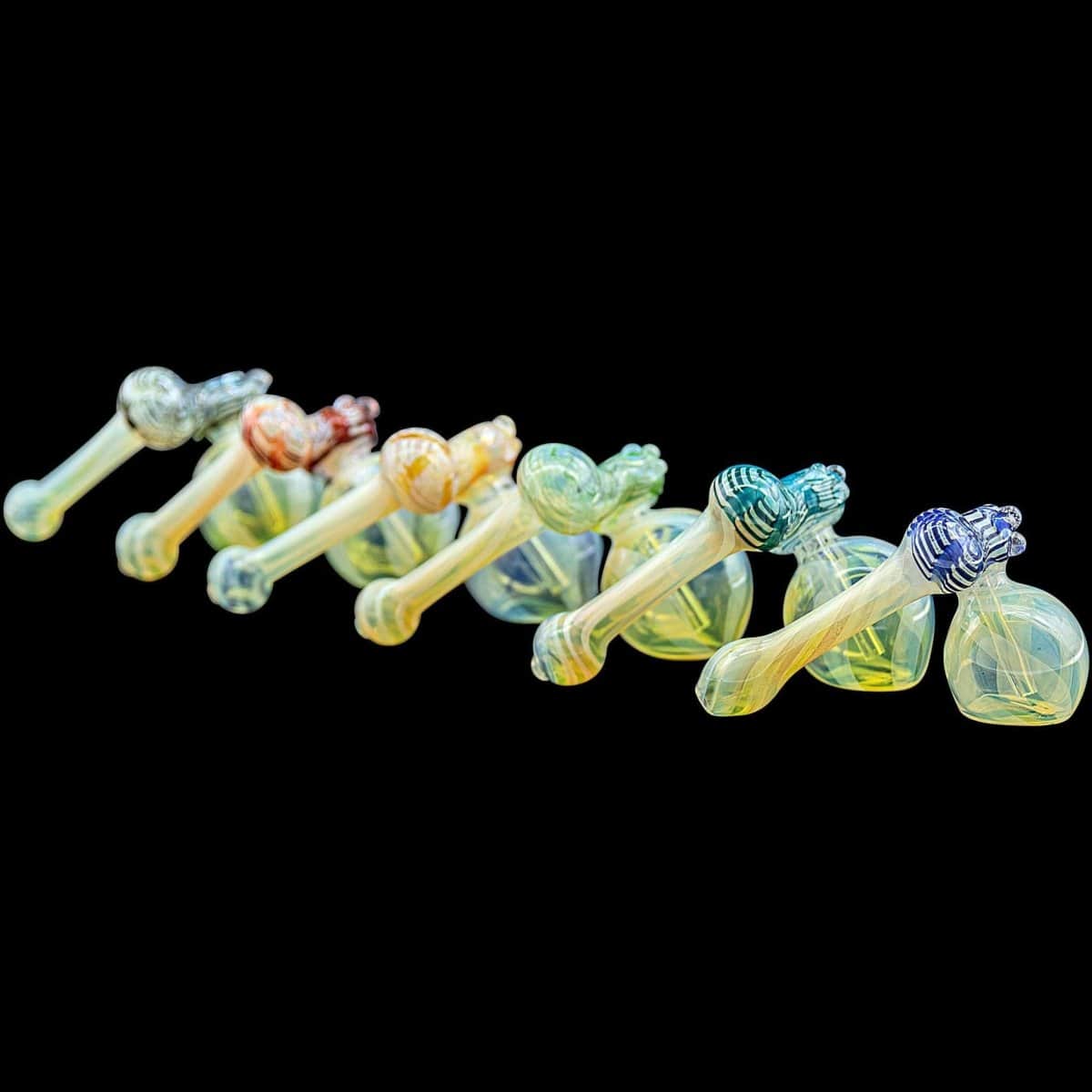 A side view of the “Raked Sidecar” Fumed Sidecar Bubbler Pipe in assorted colors, showcasing its curved form against a black background.
