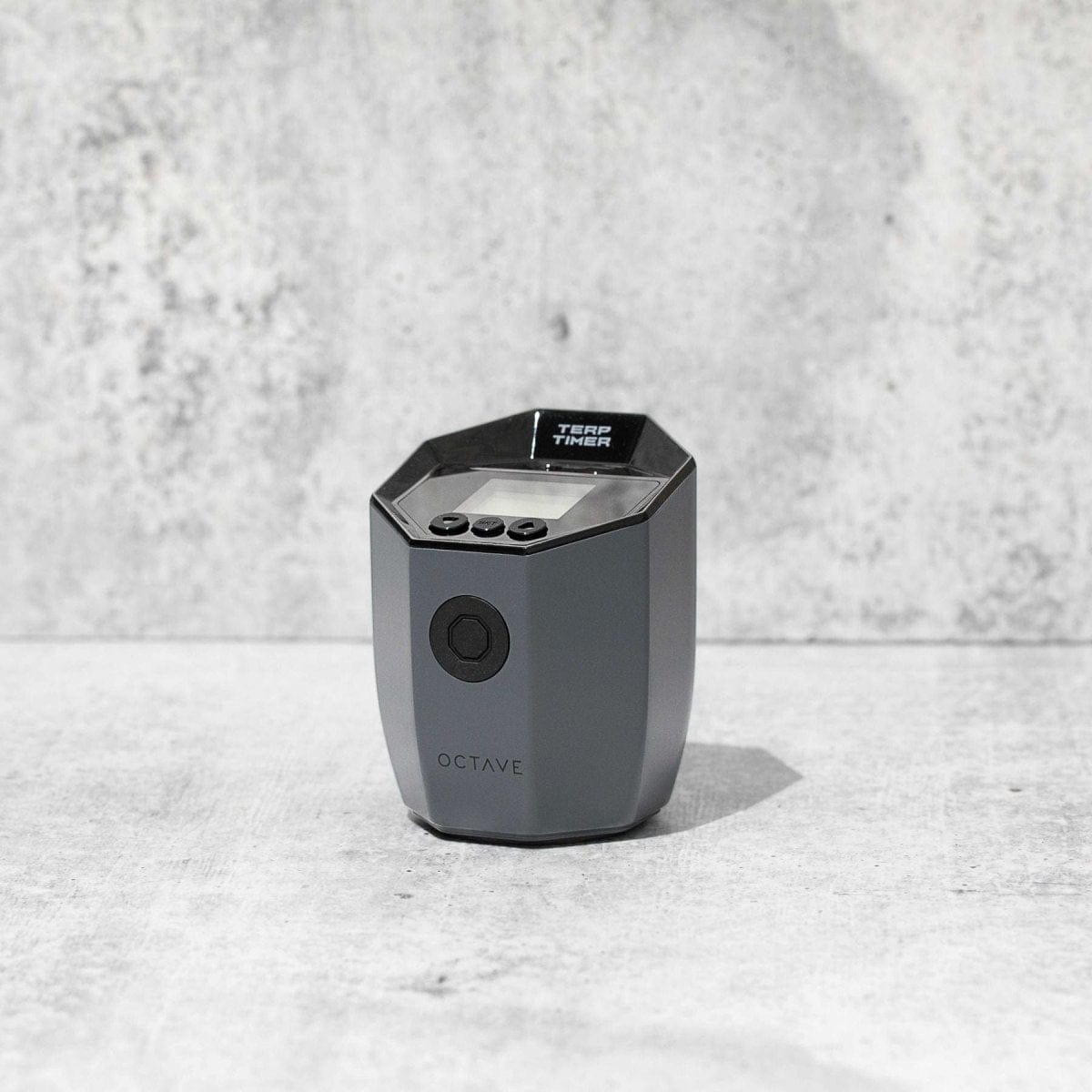 Front view of the Octave Terp Timer, a small, black device sitting on a textured gray surface with soft lighting.