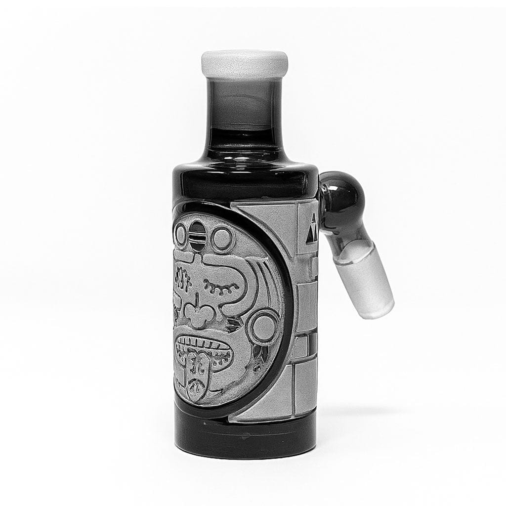 Centered front view of the Milkyway Maya Wet Ash Catcher showing a carved circular Mayan face motif on a short black glass cylinder with a side joint.