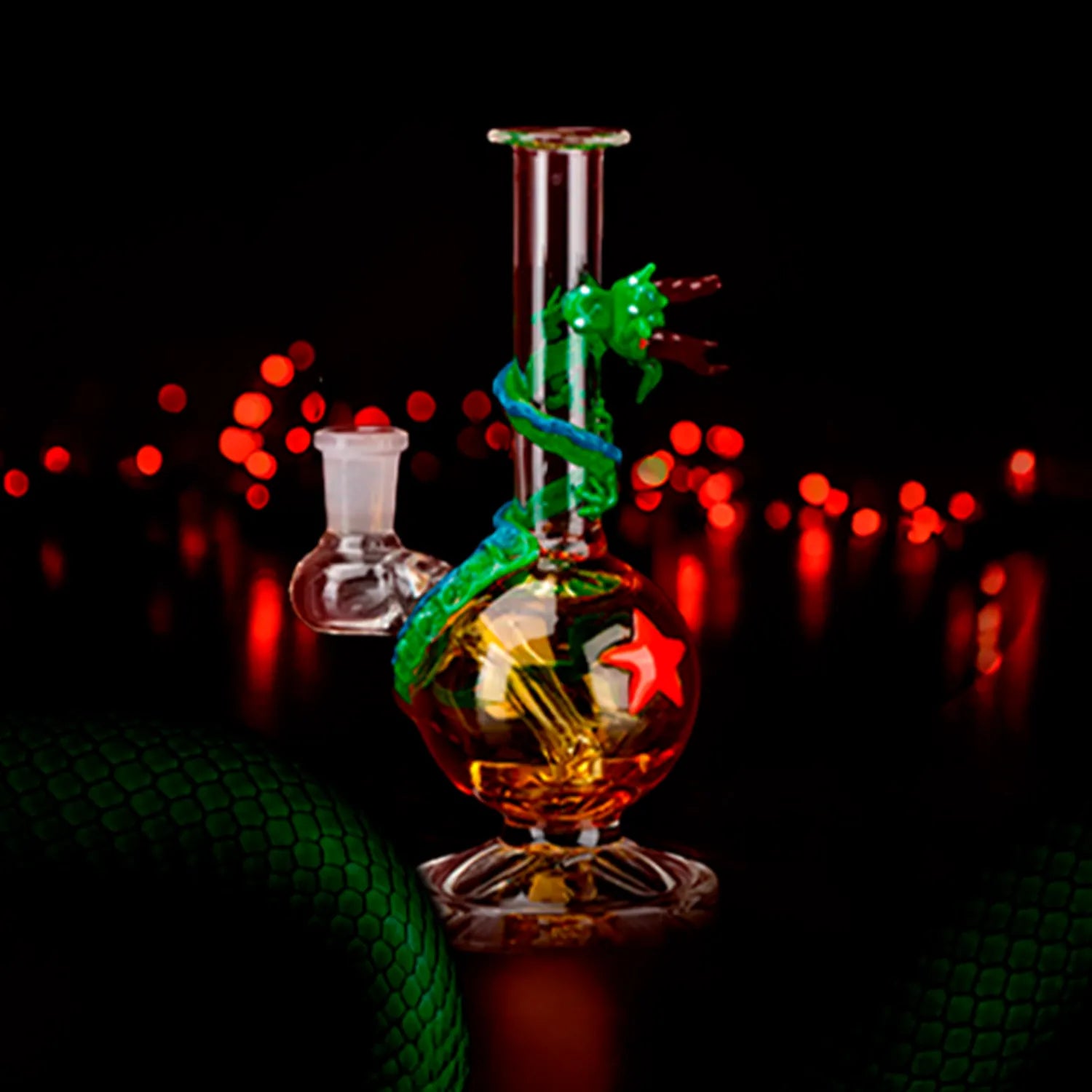 Centered front view of the Dragon Sphere Mini-Tube with a glowing orange spherical chamber wrapped by a green glass dragon against a dark background with red bokeh lights