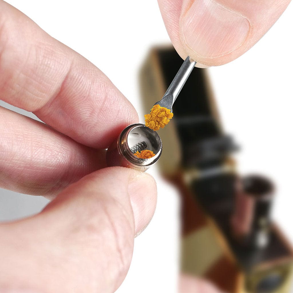Close-up of a hand holding a Ryotâ® 3 Pack Of Extra Coils For 710 Wax Tank - New coil as a dab tool deposits golden concentrate.