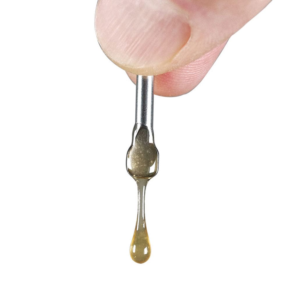 Close-up of a fingertip holding the Ryotâ® 3 Pack Of Extra Coils For 710 Wax Tank - New coil with a single amber drop of oil suspended from its tip against a white background