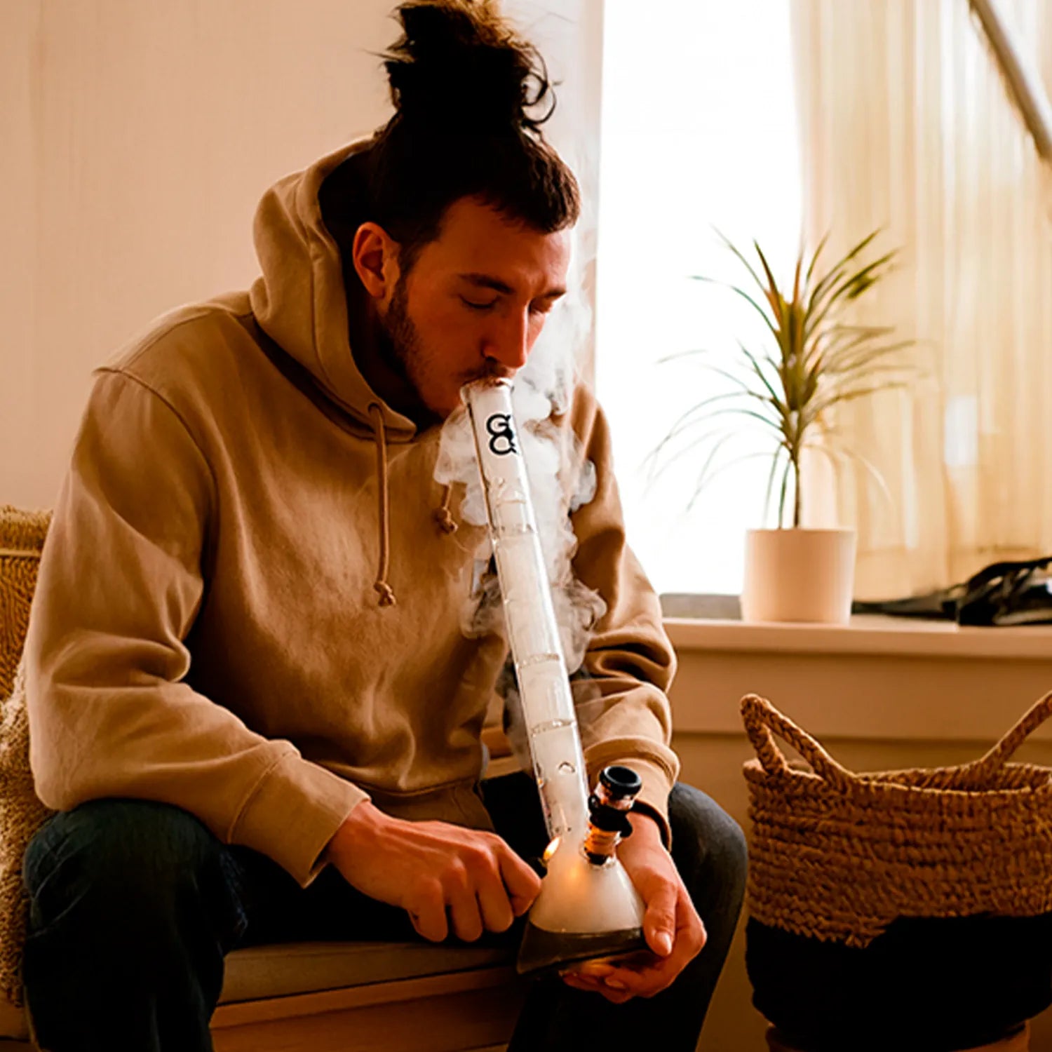Side view of a seated person inhaling from a Glasscity Beaker Ice Bong with Double Tree Perc-Blue, smoke rising from the tall clear glass tube.
