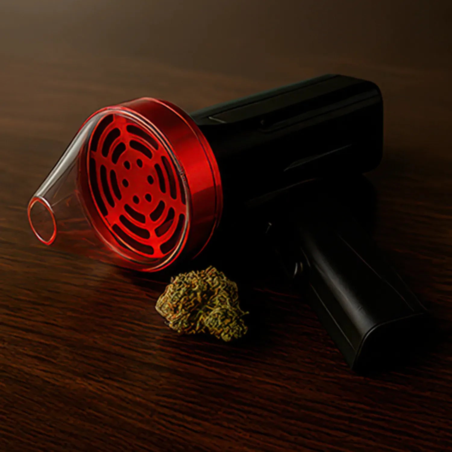 Angled close-up of the red Cloudious9 The Auto9 - Fully Automatic Grinder's clear front chamber and black body resting on a dark wood surface with a small bud nearby