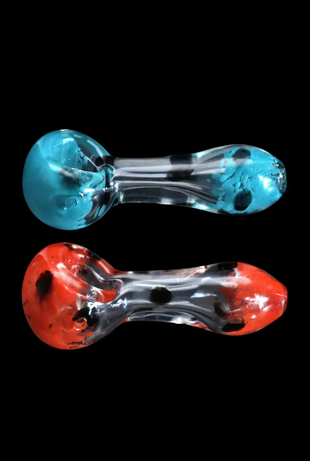 Top-down view of two DHC Color Frit with Dots Spoon Pipe - 2.5 in. glass handpipes, one turquoise and one red, shown side-by-side on a black background.