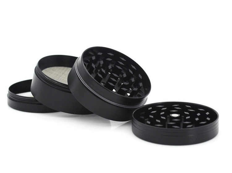 Angled view of a gunmetal 4-Piece Zinc Grinder showing its four separated magnetic chambers and diamond-shaped teeth on a white background.