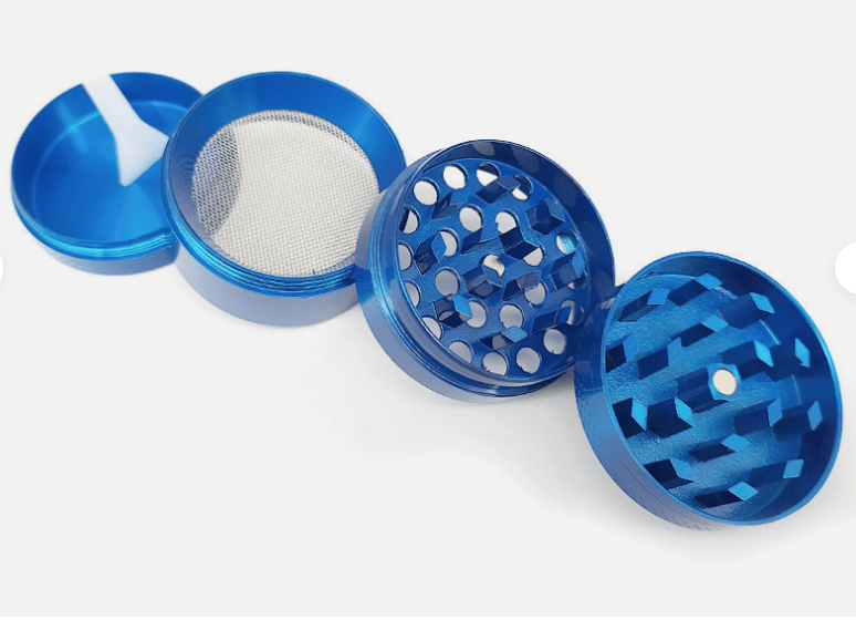 Angled top-down view of the blue 4-Piece Zinc Grinder opened to show its magnetic lid, mesh screen, and two toothed grinding chambers