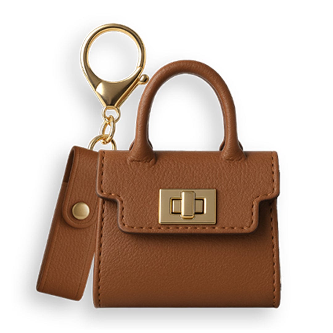 Top-down view of a small brown Hermione Penjamin Pursejamin Vaporizer keychain purse with gold hardware and a matching strap against a white background