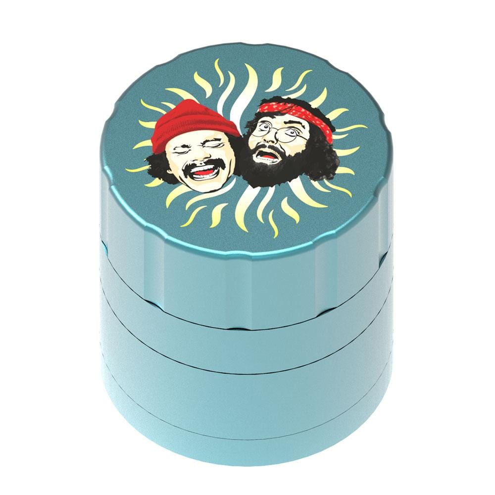 Top-down view of the black Up In Smoke 40th Anniversary 53mm 4-Piece Grinder showing a teal lid printed with two laughing faces surrounded by yellow sunrays.