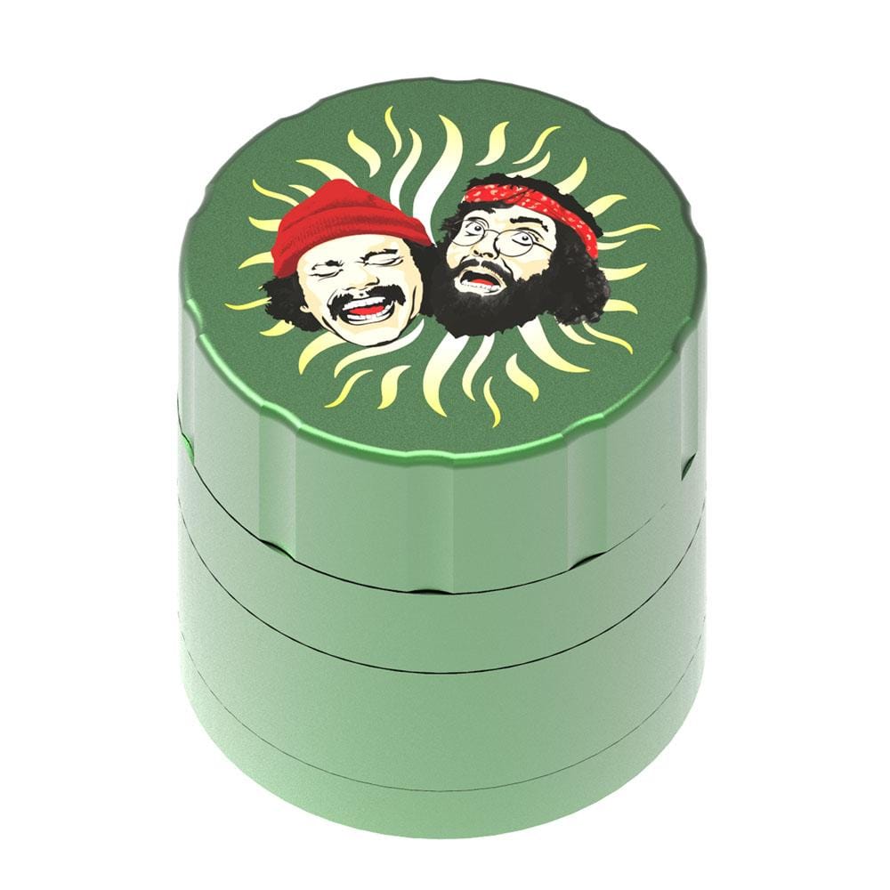 Top-down view of a red-topped Up In Smoke 40th Anniversary 53mm 4-Piece Grinder showing two illustrated faces surrounded by sunrays on a green body.
