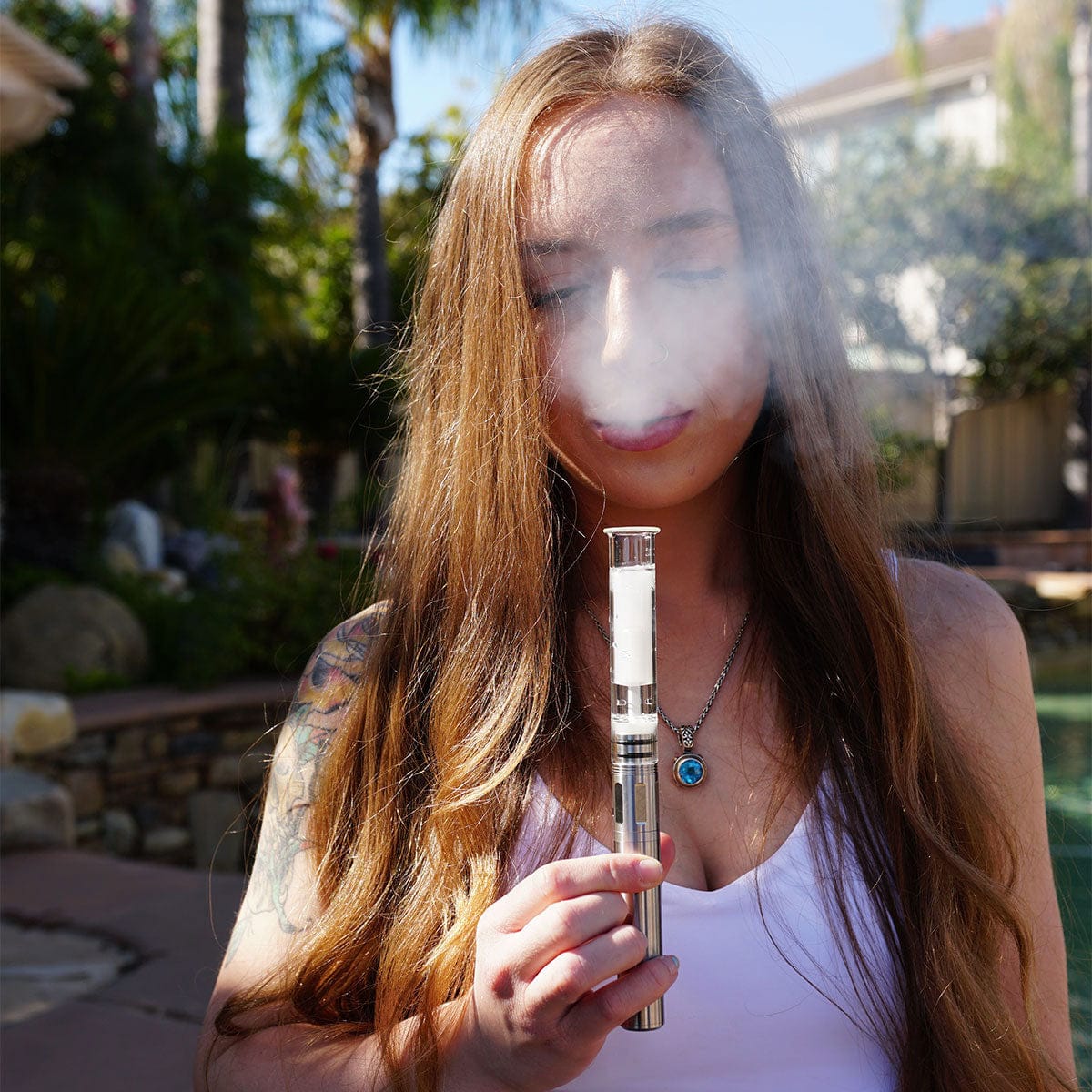 Close-up outdoor portrait of a woman exhaling vapor while holding the Cipher NOVA | Iridescent - V2 near her face.