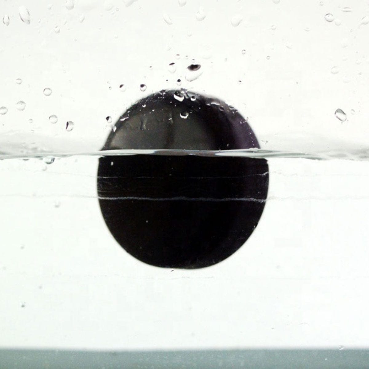 Close-up side view of the black Cipher Stor8 Smell-proof Herb Container | 8g half-submerged in clear water with droplets on a white background