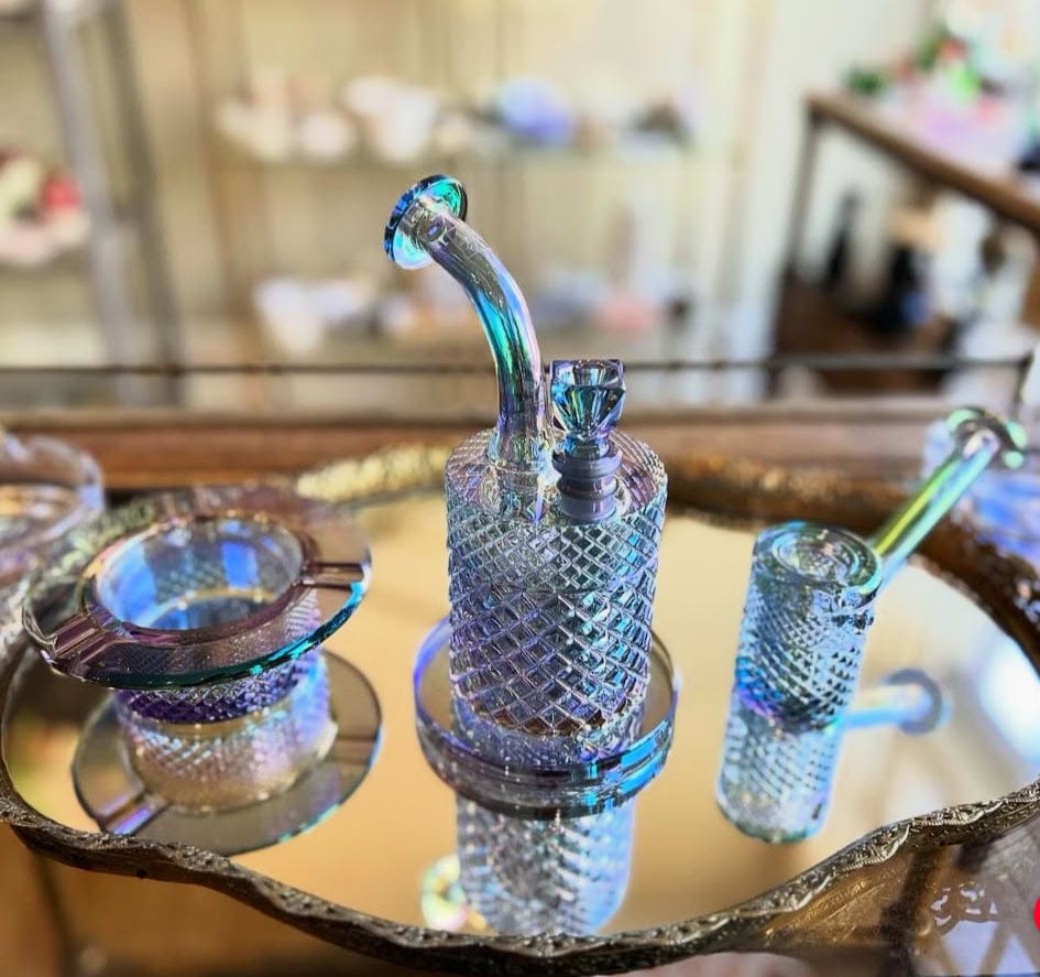 Close-up of the Twenties Collection Hand Pipe | Mermaid shown upright on a mirrored tray, its iridescent, textured glass reflecting blue-green hues.