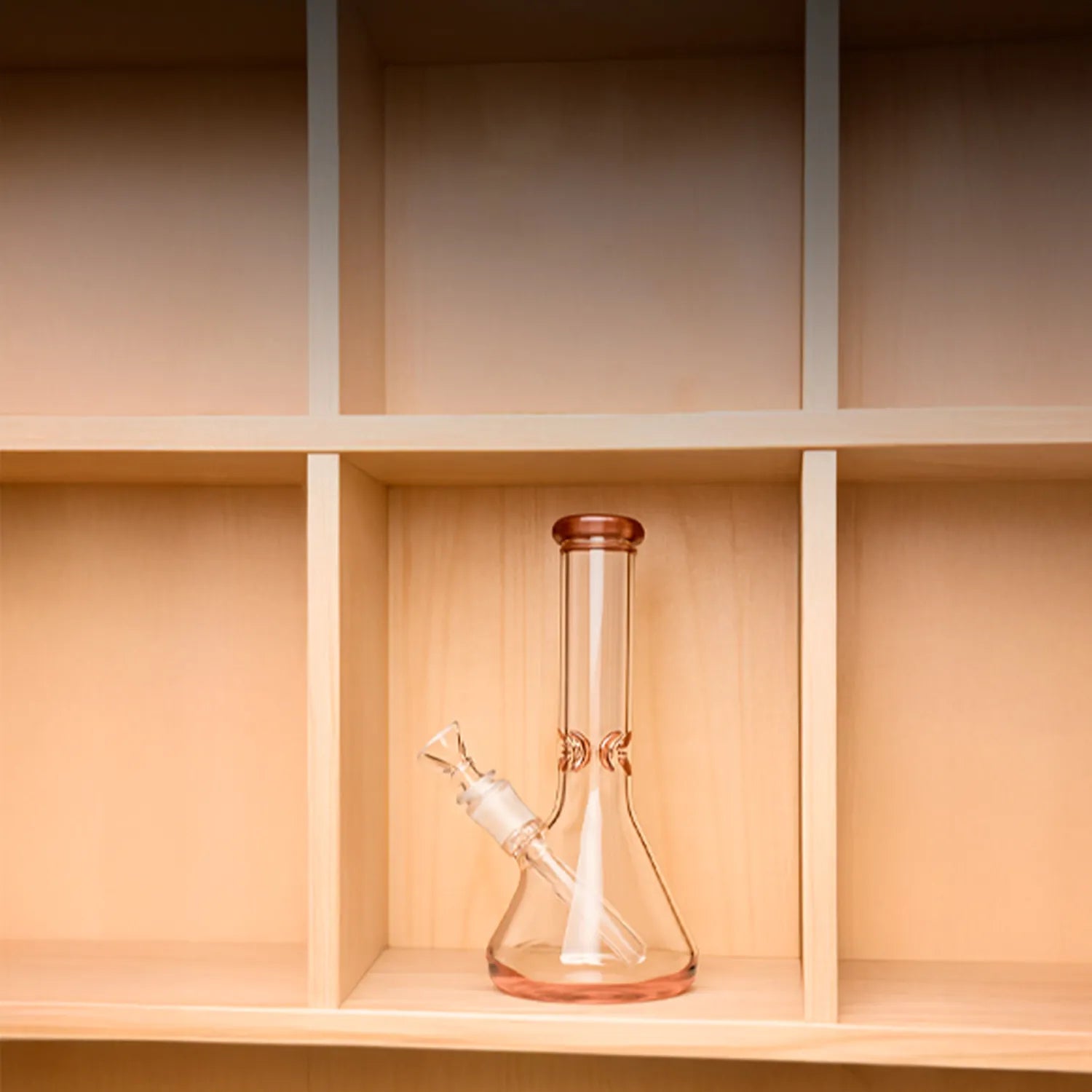 Centered front view of the DHC 9mm Big Base Beaker w/ Color Accents Bong - 12 in. resting on a light wood cubby shelf, showing its transparent black glass beaker base and straight neck.