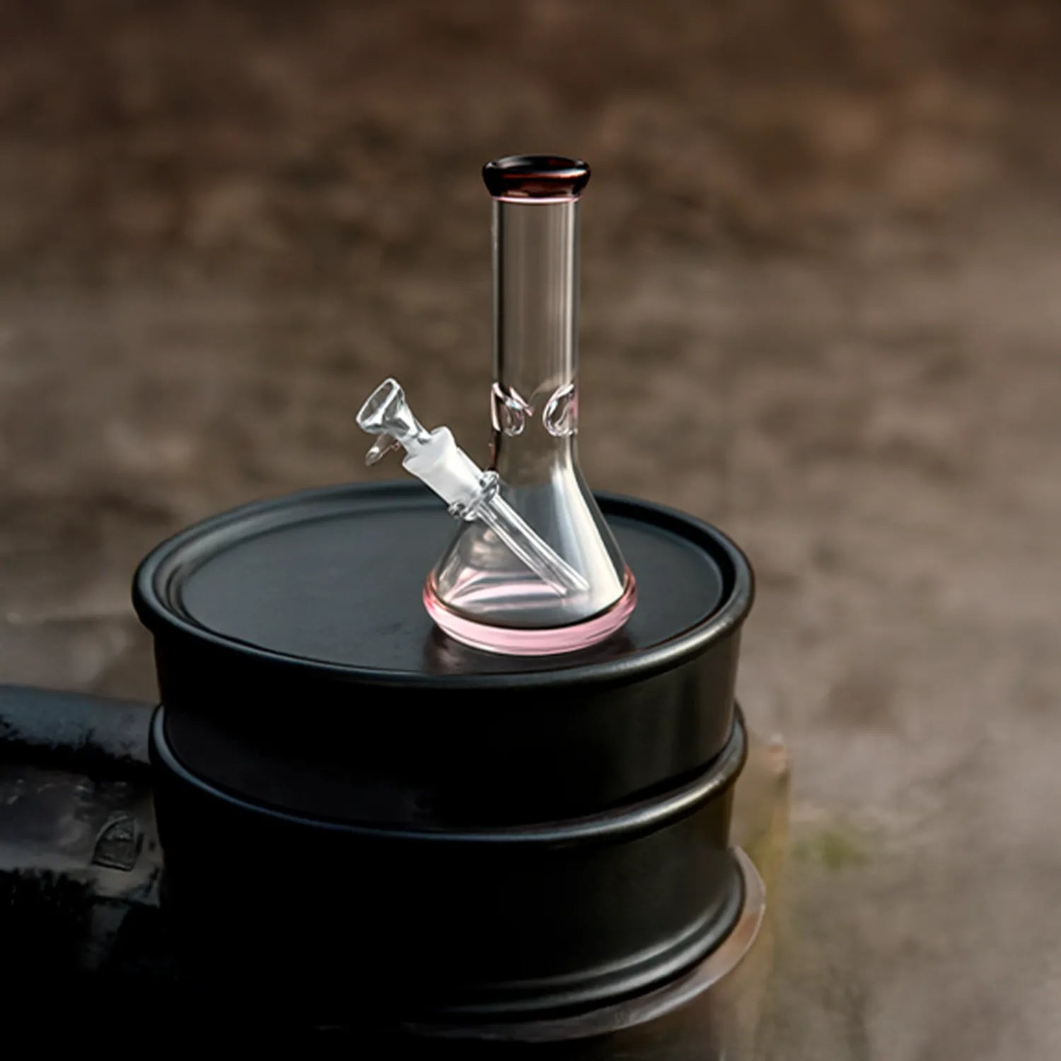 Close-up, slightly angled view of the DHC 9mm Big Base Beaker w/ Color Accents Bong - 12 in. showing clear glass with pink rim accents on a dark drum.