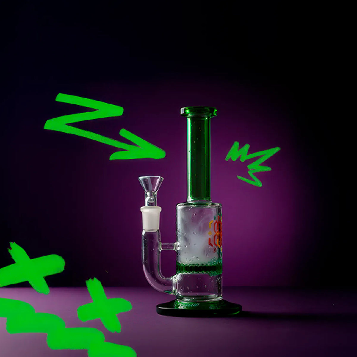 Side view of the Straight Tube Colored Glass Bong | Blue standing on a purple surface against a dark purple background with green graffiti accents.