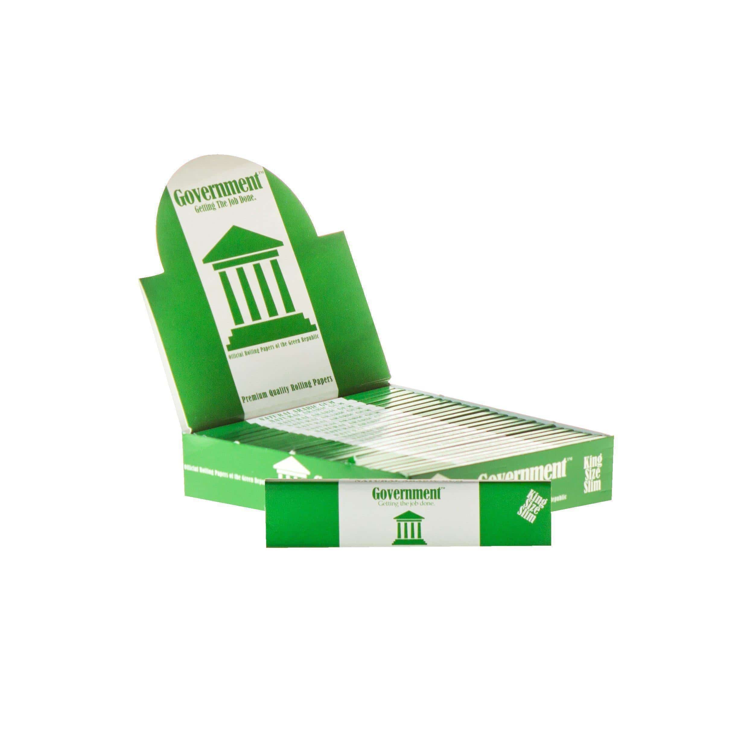 Diagonal close-up of an open green box of Government Rolling Papers - King Size showing stacked slim packs and a white pillar logo on the inner flap