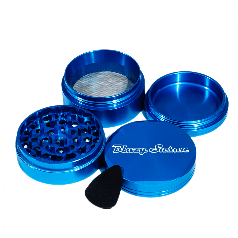 Top-down view of a metallic blue Blazy Susan 4-pc 3 Chamber Grinder with its lid, grinding plate, mesh chamber and catch tray arranged on a white background.