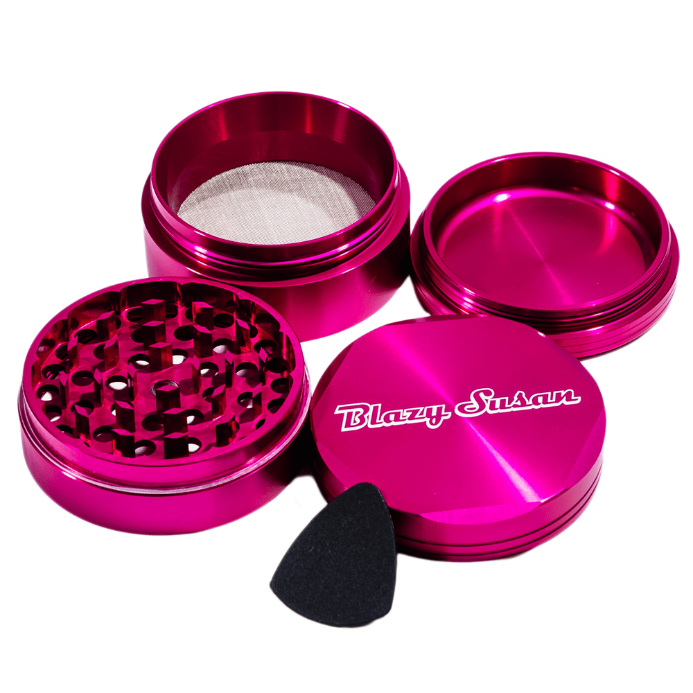 Top-down view of a purple Blazy Susan 4-pc 3 Chamber Grinder with its four shiny parts and a small black pick arranged on white.