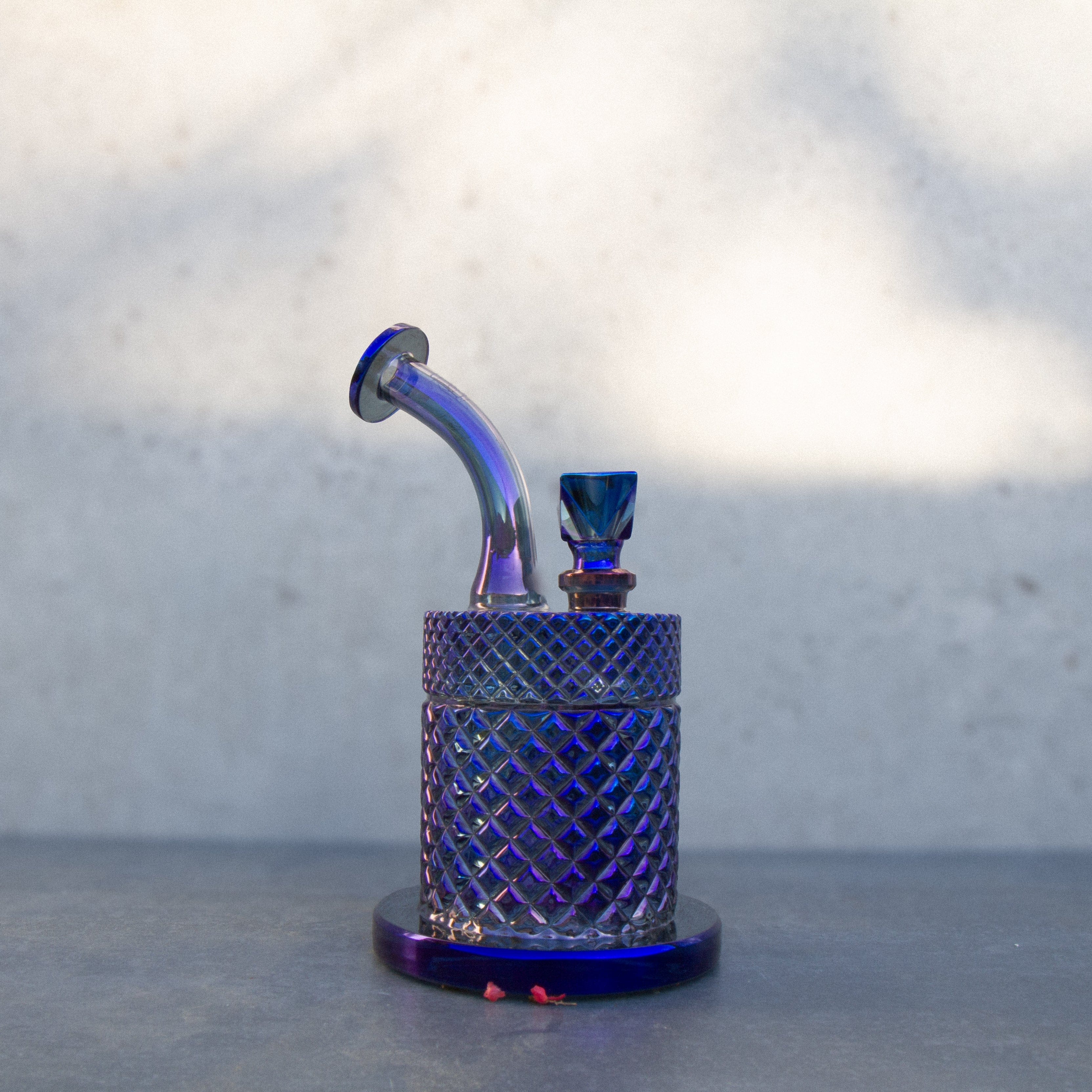Close-up of the iridescent blue Twenties Collection Bong | Midnight showing its curved mouthpiece and textured cylindrical body against a soft gray background