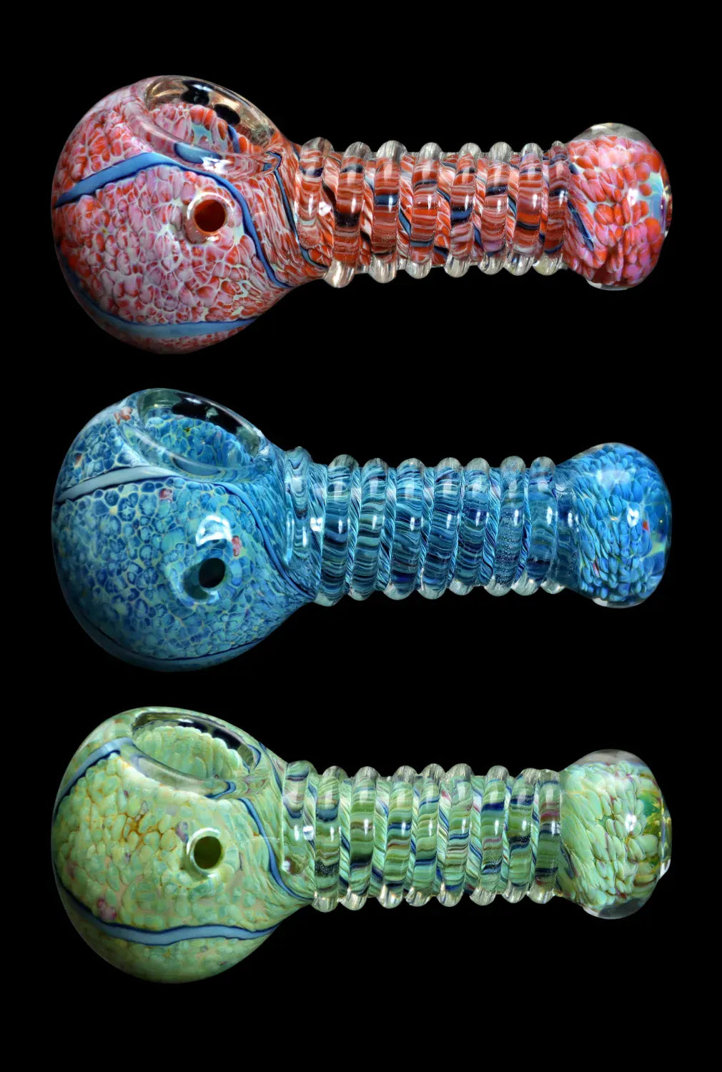 Three horizontal DHC Twisty Wrap Spoon Pipe - 5in. glass pipes stacked on black, showing ribbed clear necks and mottled red, blue, and green bowls