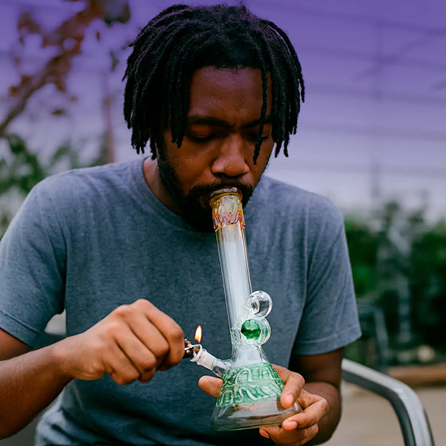 Close-up of a person using the DHC Mushroom Marble Bong - 18 in., holding a green-marble beaker bong upright while lighting the bowl.