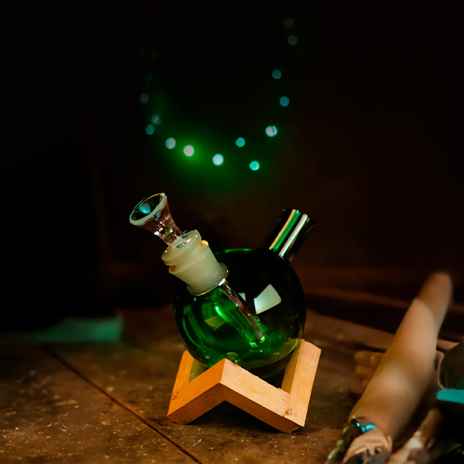 Angled close-up of the amber Art of Smoke Orb Bubbler resting in a wooden star stand with green bokeh lights in the dark background
