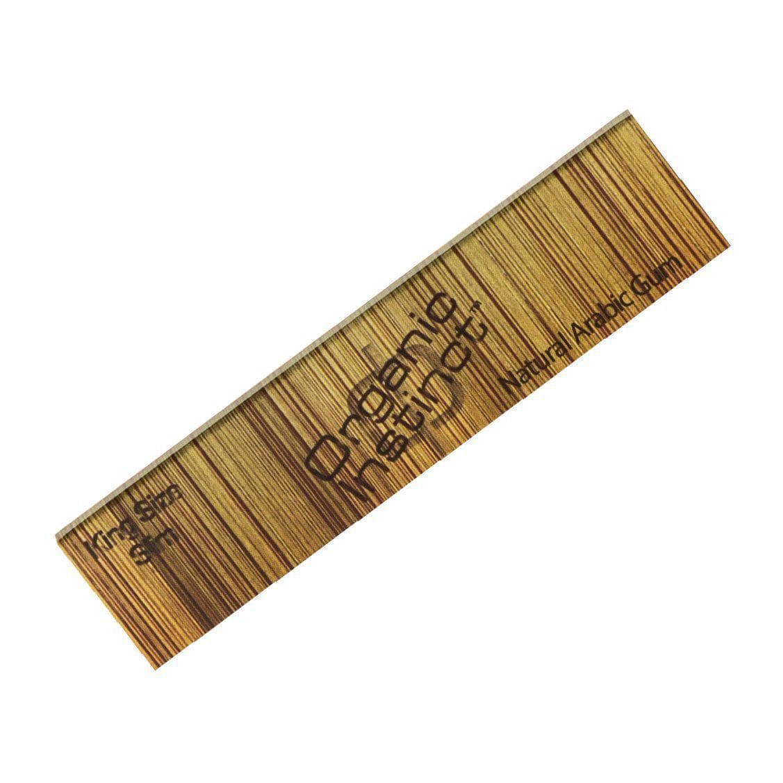 Diagonal close-up of a wood-grain strip printed with the Organic Instinct Hemp Rolling Papers - 1 1/4" logo and fine vertical grain lines