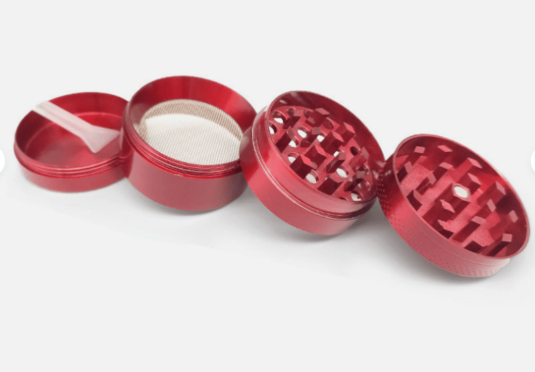 Angled close-up of a rose gold 4-Piece Zinc Grinder laid open in four parts on a white surface, showing textured teeth, a mesh screen, and a small plastic scraper.