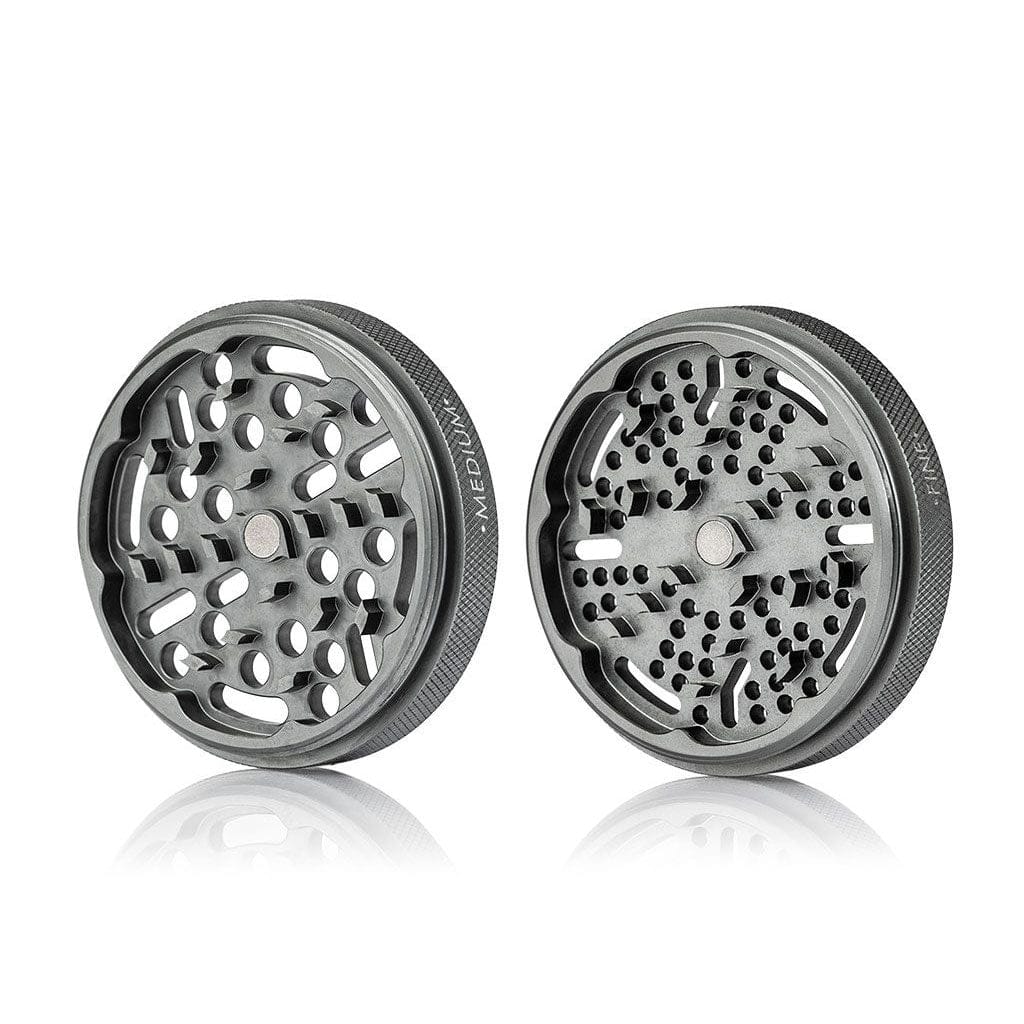 Angled front view of two grey metal Ryot Gr8Tr Solid Body Grinder halves showing their patterned teeth, textured rims, and soft studio reflection