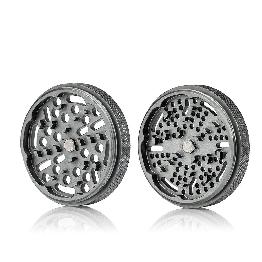 Studio-lit front-angle view of two metal grinder halves showing interlocking teeth and knurled edges for the Ryot Gr8Tr Solid Body Grinder