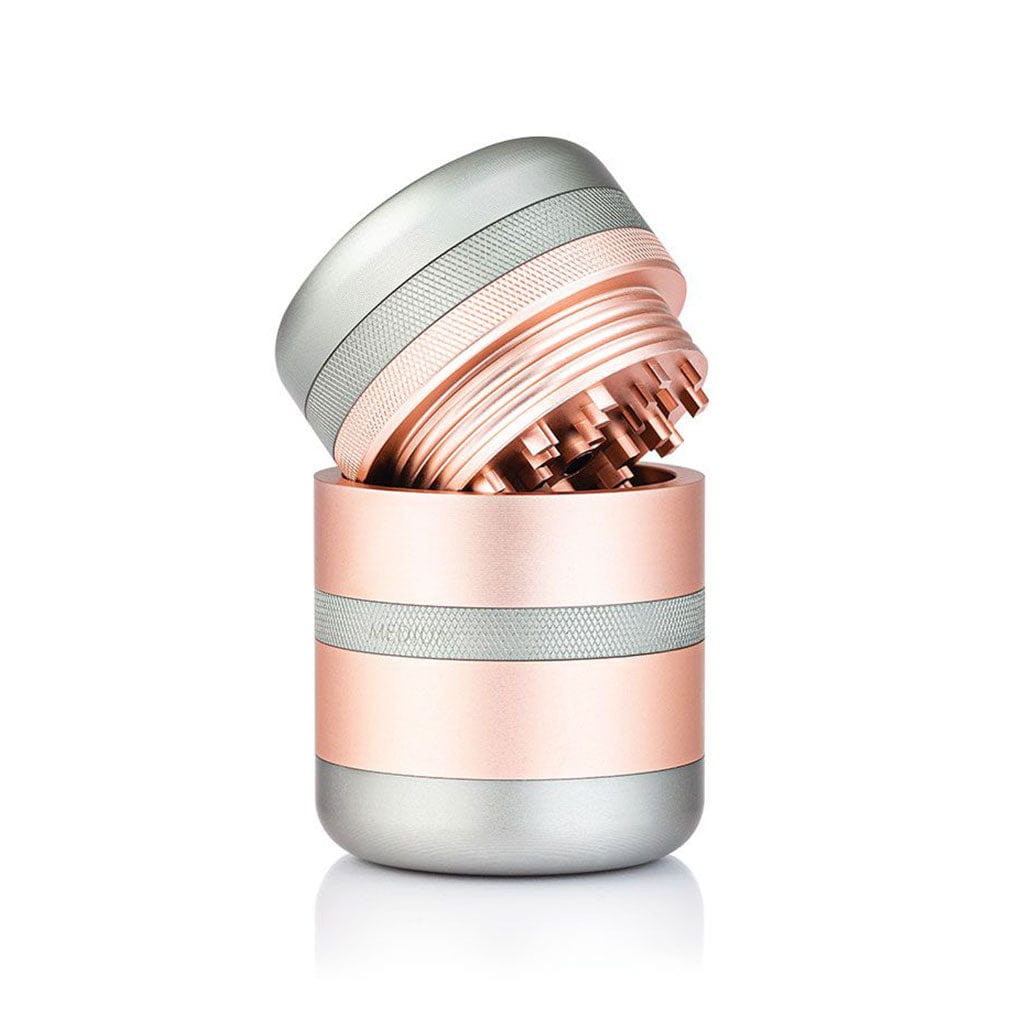 Angled close-up of the rose gold and silver Ryot Gr8Tr Solid Body Grinder with its top half tilted to reveal sharp internal teeth.