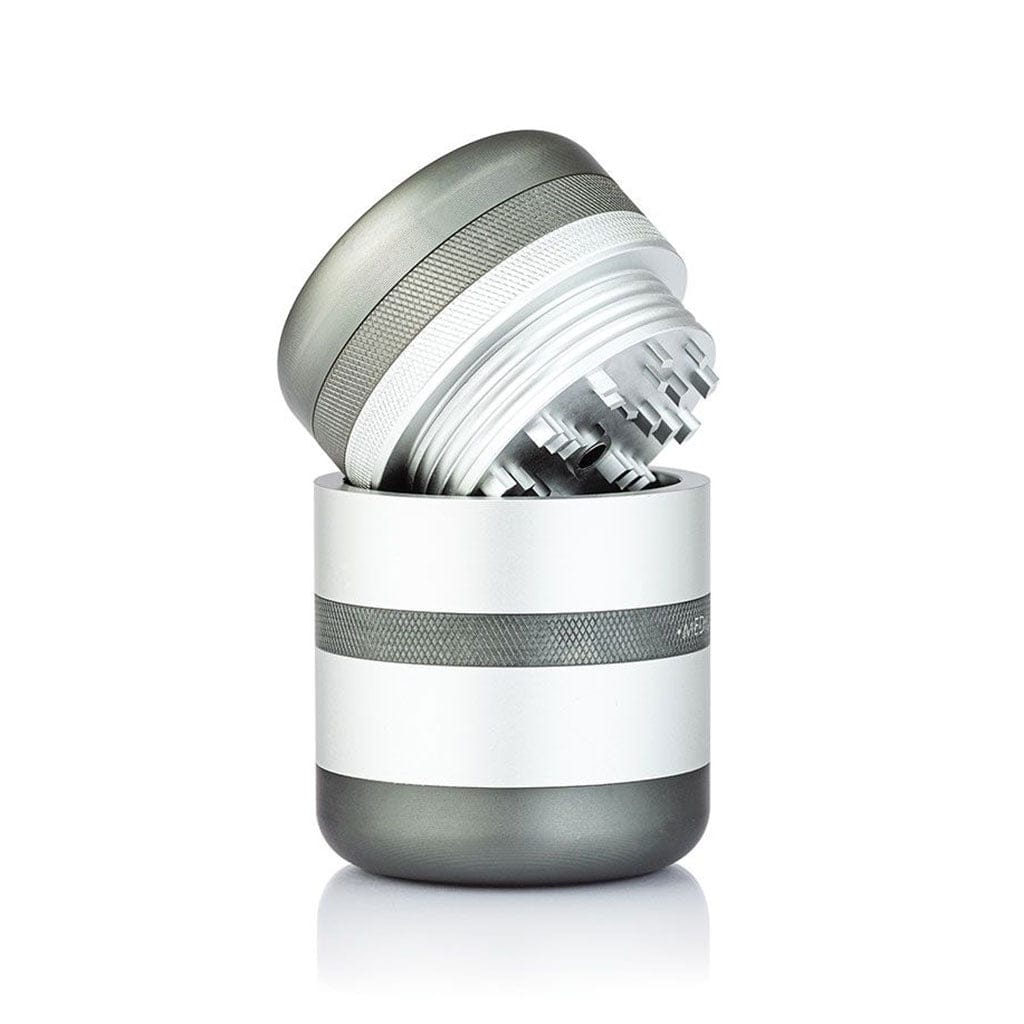 Angled close-up of a silver-and-white Ryot Gr8Tr Solid Body Grinder with its top half tilted to show internal teeth and threaded rim.