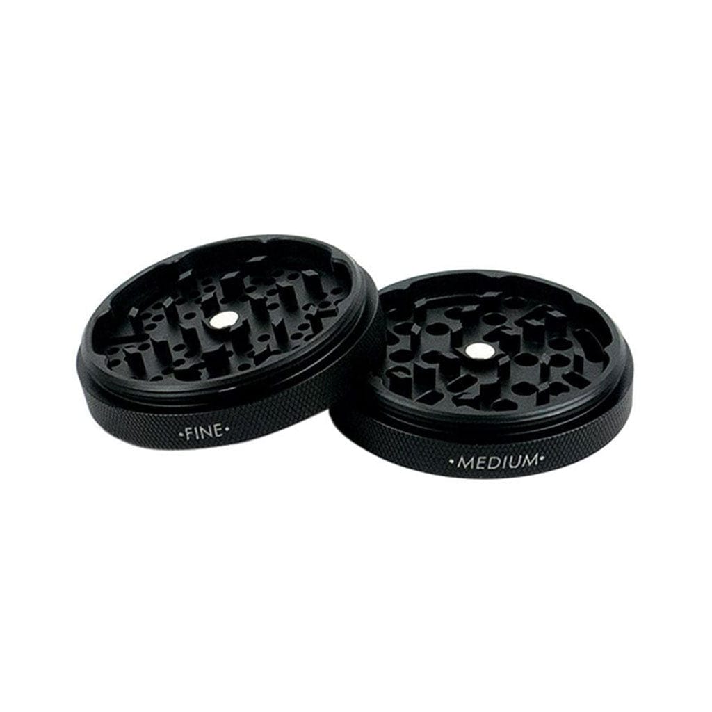Angled close-up of two black Ryot Gr8Tr Solid Body Grinder halves showing interlocking teeth and labeled "FINE" and "MEDIUM" on a white background