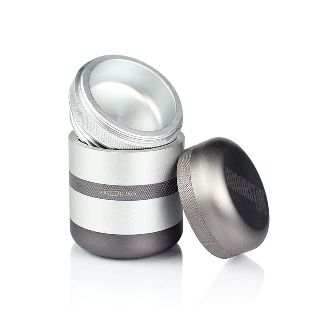 Angled studio shot of the matte silver Ryot Gr8Tr Solid Body Grinder with its lid removed and resting beside the stacked, knurled chambers.