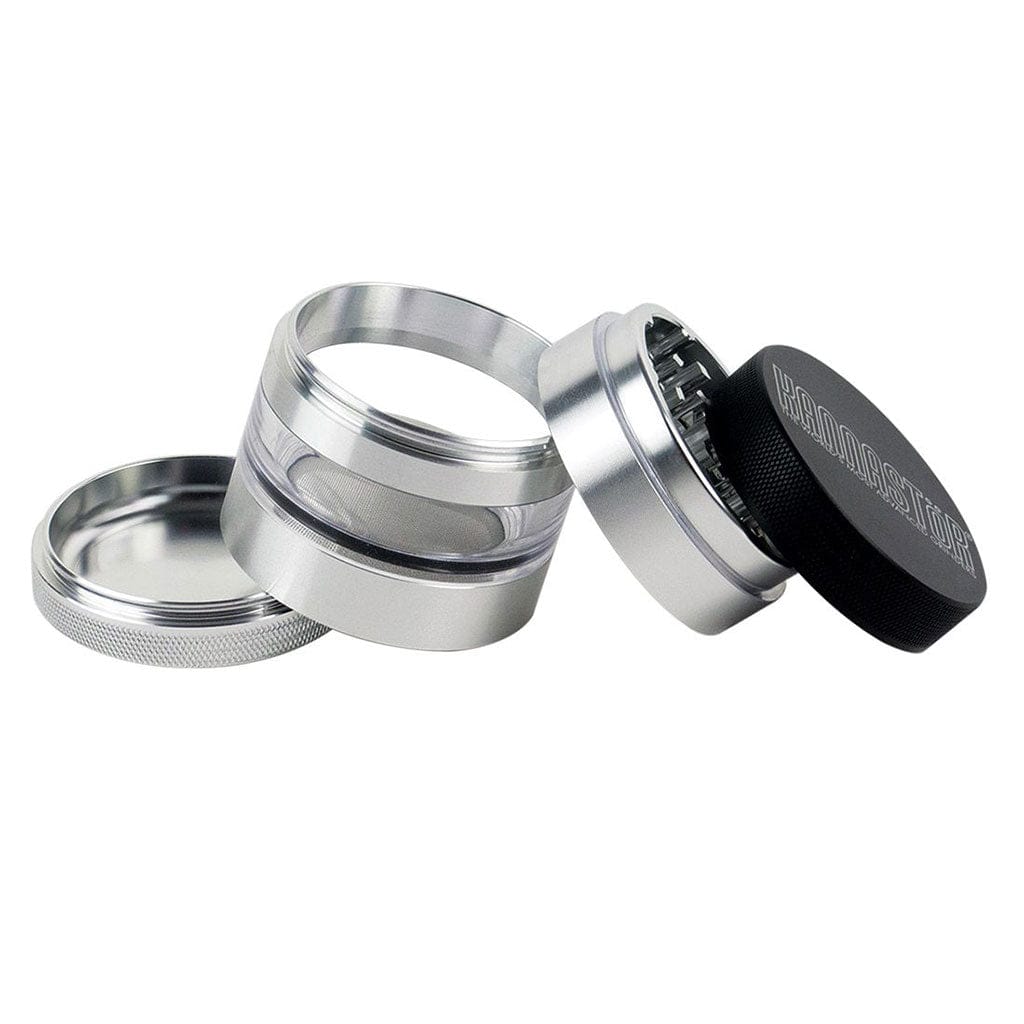 Angled close-up of the disassembled Ryot 4Pc Jar Body Grinders showing silver metal chambers, a mesh screen, and a black textured top on a white background