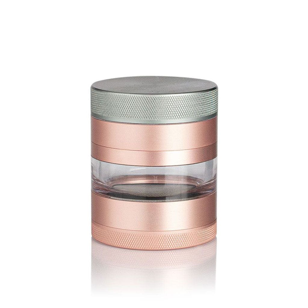 Centered front view of a rose-gold and silver Ryot 4Pc Jar Body Grinders on a white reflective surface showing its clear middle chamber and textured metal lids.