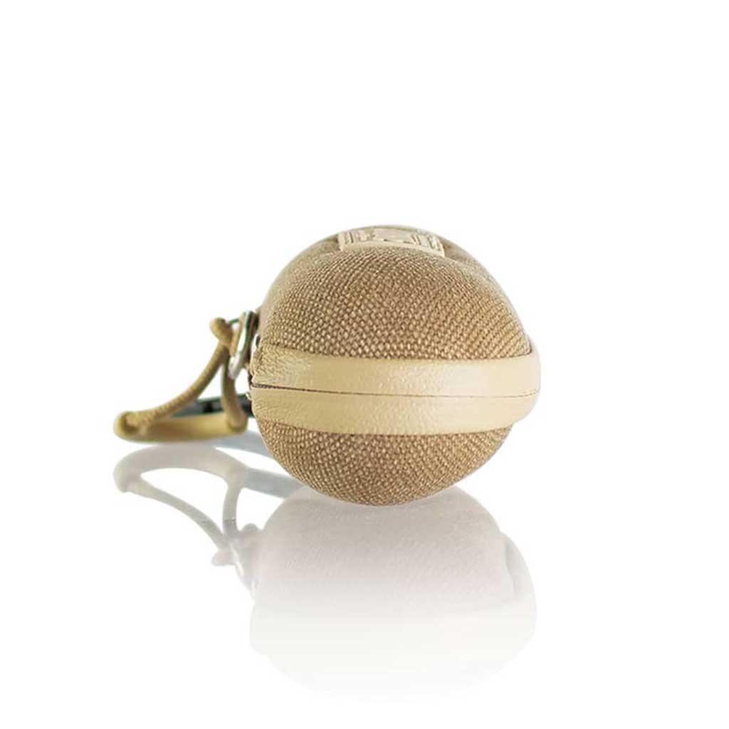 Low-angle close-up of a tan Ryot Hardcase keychain pod resting on a reflective white surface with its strap trailing behind.