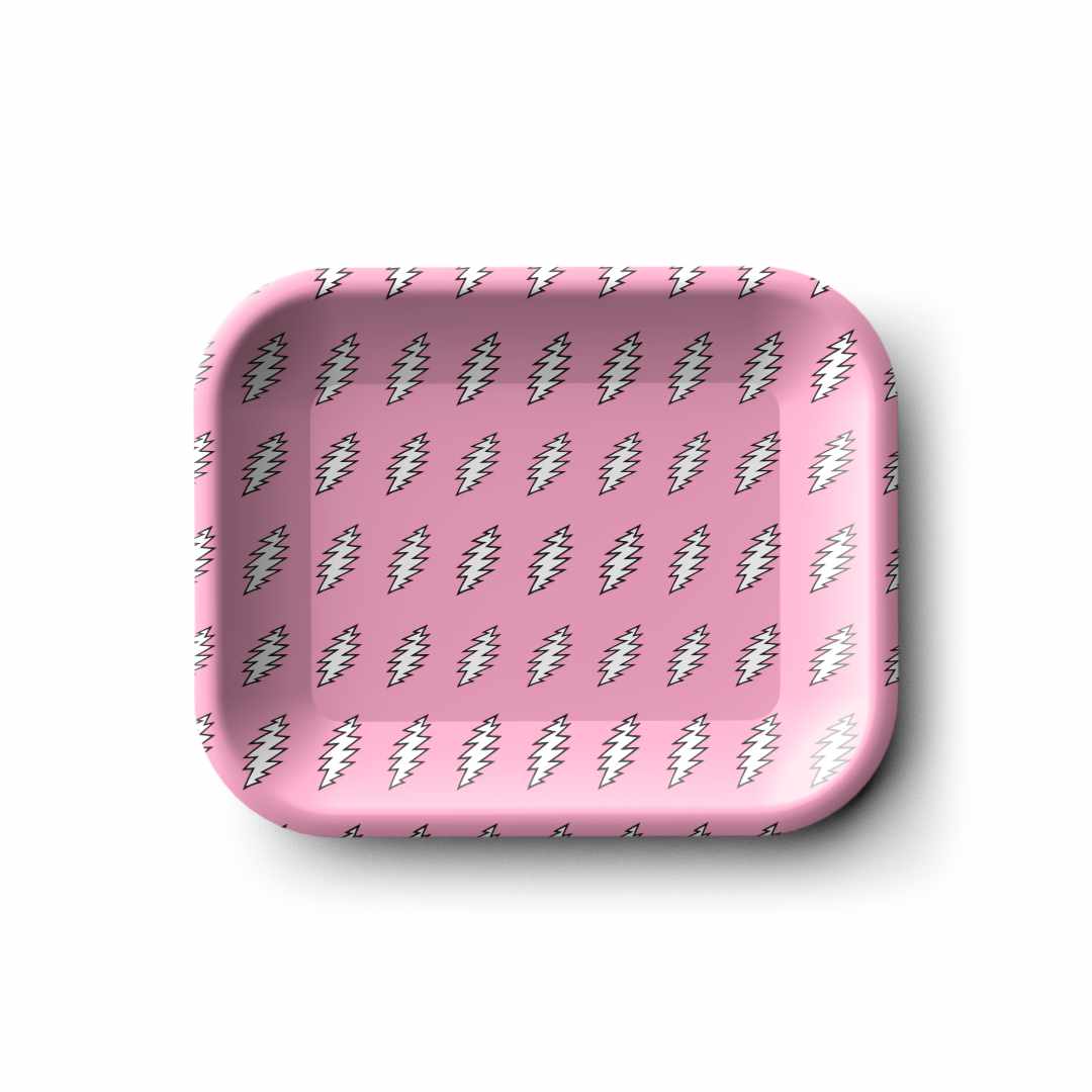 Top-down view of a small Blazy Susan Grateful Dead Metal Rolling Tray - Small in pink, showing repeating white lightning-bolt motifs and soft shadowing.