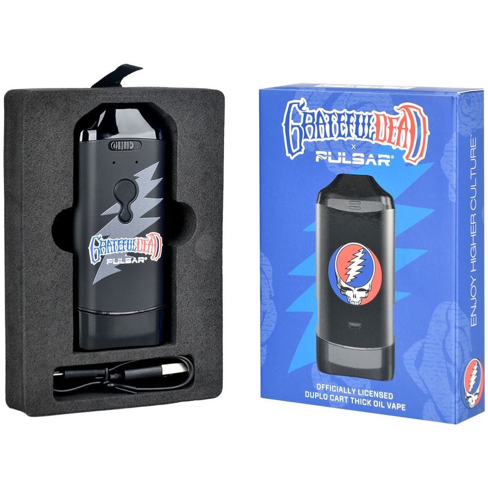 Left-angled product shot of the Grateful Dead X Pulsar Duplocart Vaporizer - 650Mah nestled in black foam beside its blue branded box showing a skull-and-lightning logo.