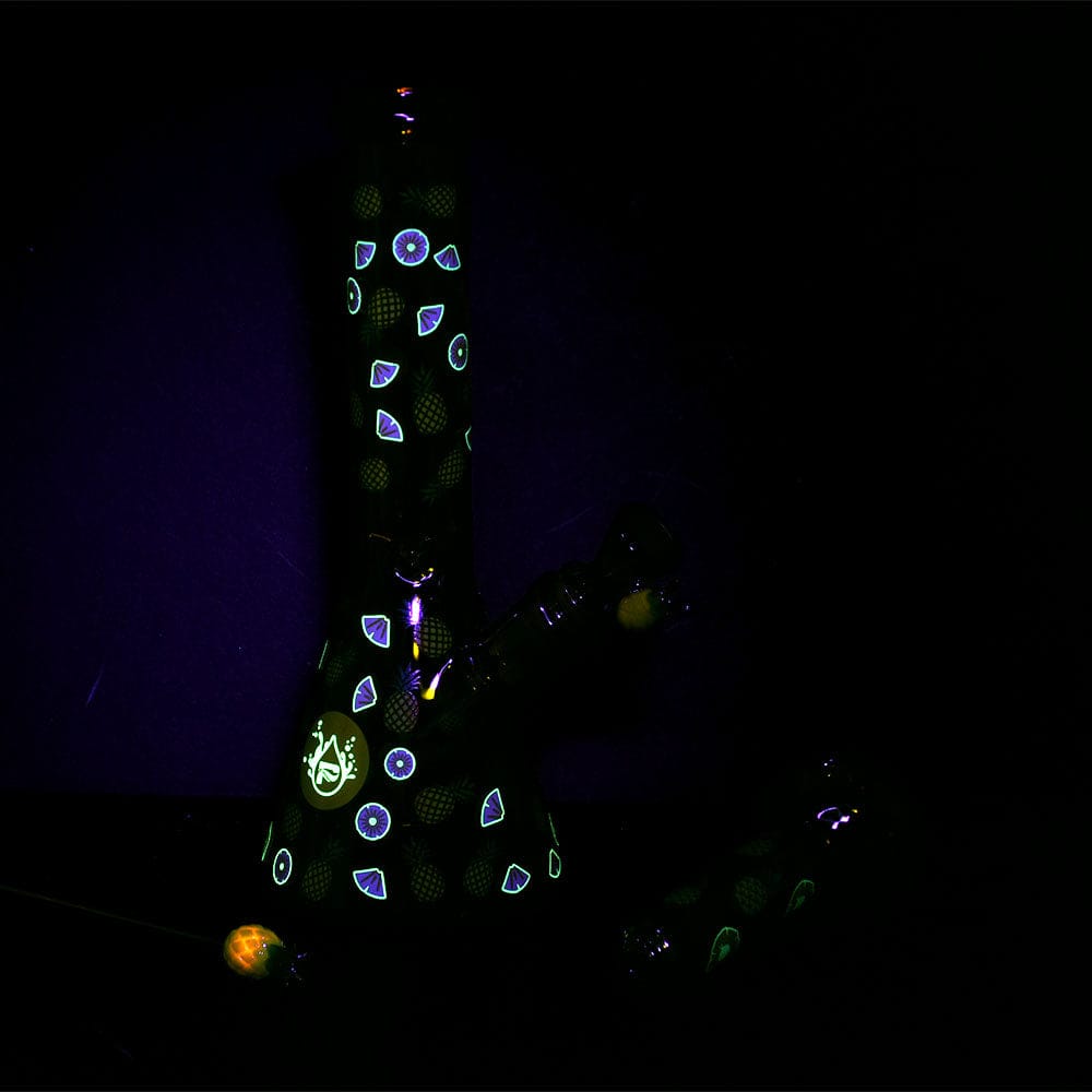 Upright front view of the Pulsar Fruit Series Pineapple Express Herb Pipe Glow Duo - 10" / 14Mm F with glowing pineapple and citrus slice motifs against a dark background