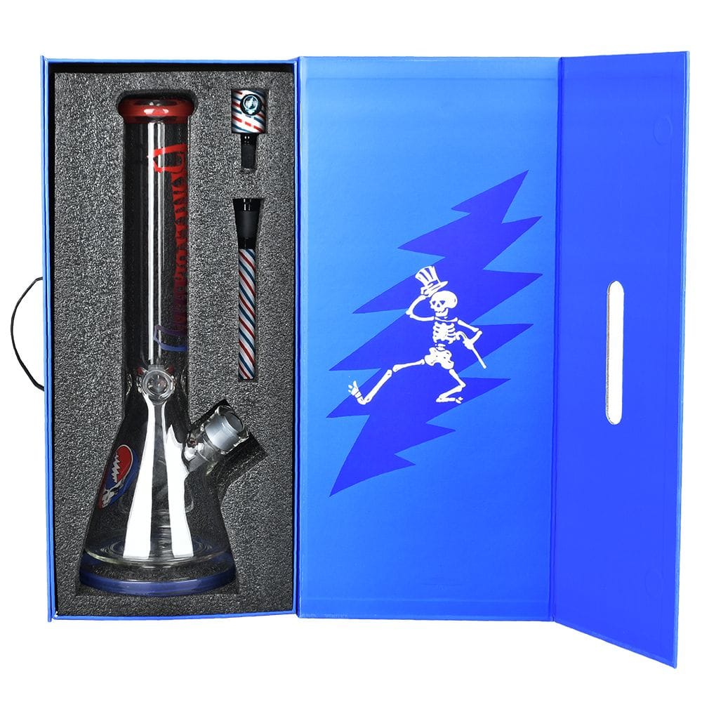 Top-down view of the Grateful Dead X Pulsar "Liberty Beaker" Bong - 15.75" / 14Mm F nestled in black foam inside a bright blue presentation box with a dancing skeleton graphic.